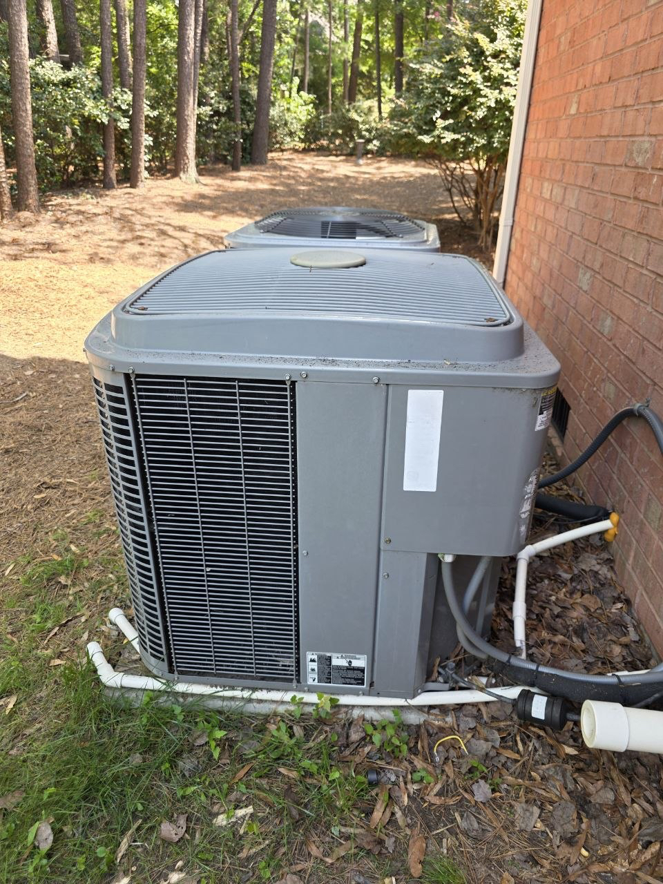 Two outdoor AC systems beside a brick home